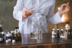 A Person in White Robe Holding a Glass Pipette